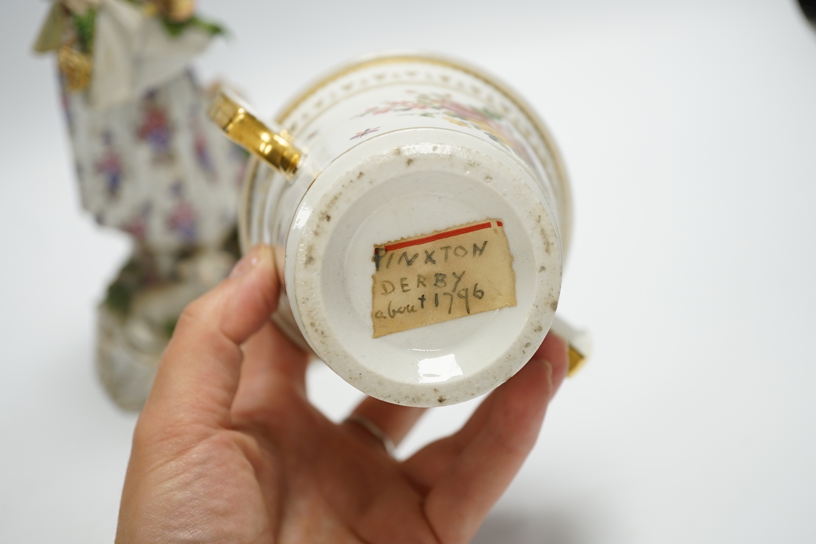 A late 19th century Continental porcelain figure of a lady, a Pinxton-type chocolate cup and cover, a Derby putti and a small Minton flower encrusted vase, figure 24.5cm (4)